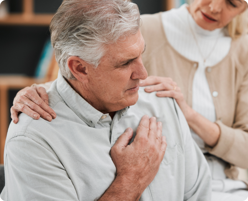Close up of a person holding their chest and another person with hands on their shoulders